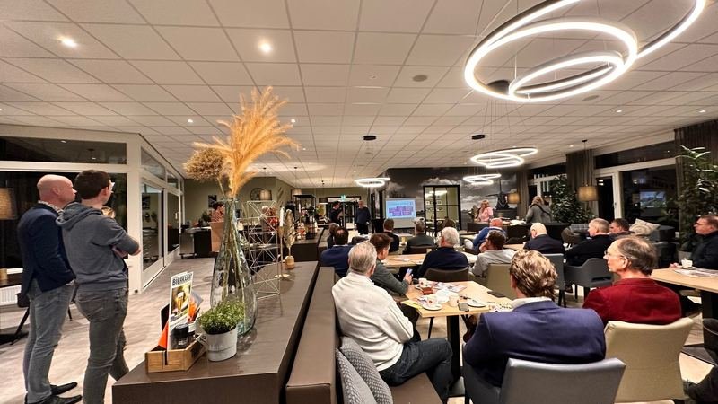Gasten aan lange tafels in de zaal